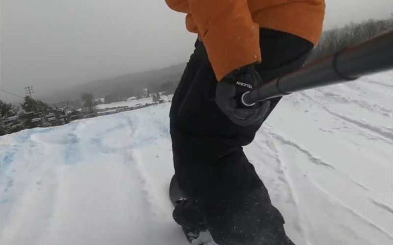 snowboarder orange jacket about to take off jump terrain park